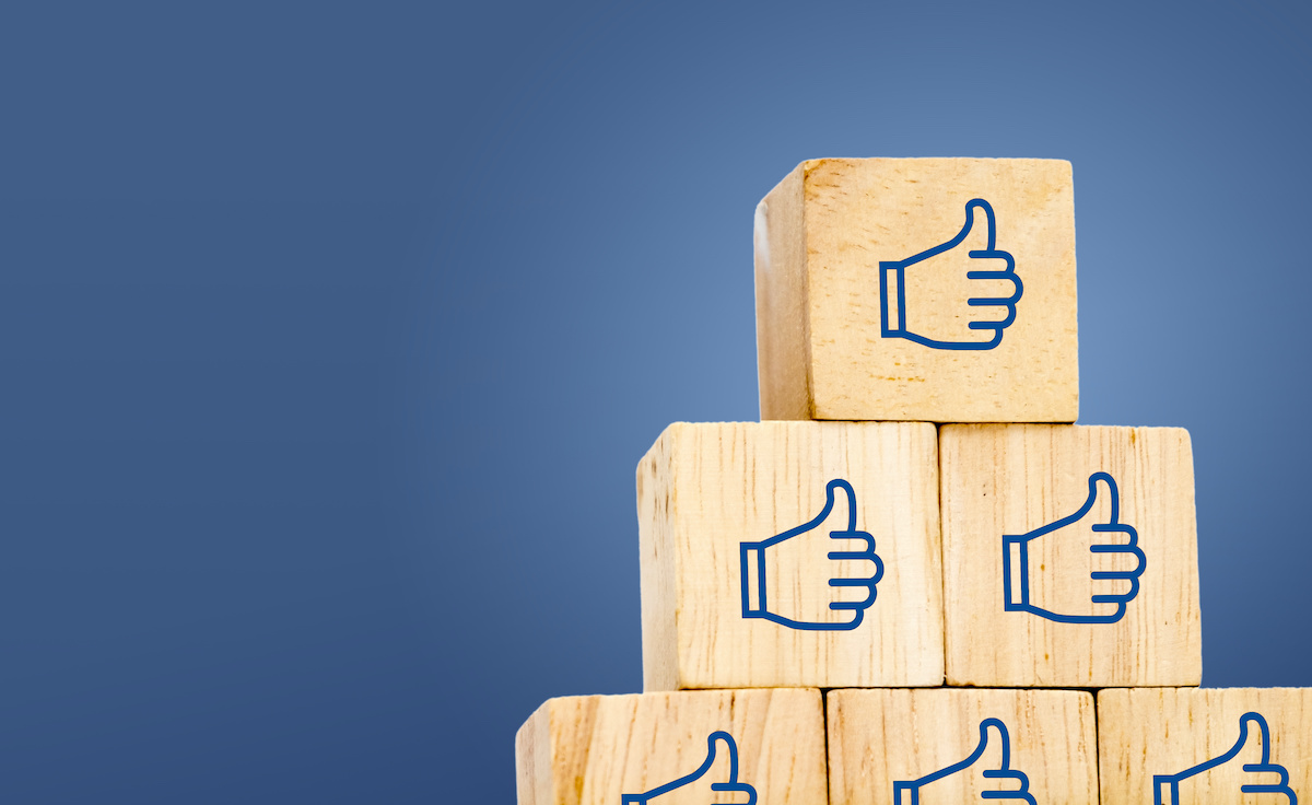 Thumb up icon on wood cube at dark blue background, leave space for adding text; blog: facebook groups