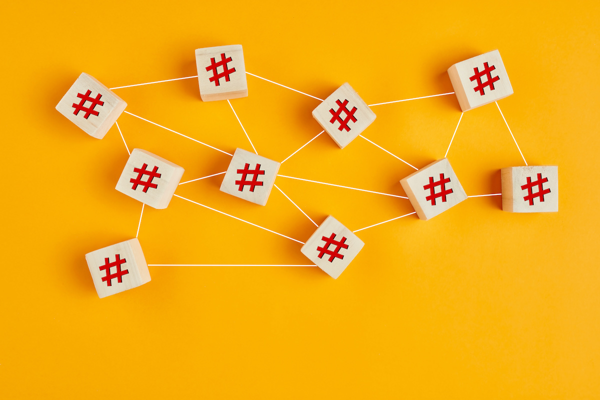 Hashtag symbols on wooden cubes connected to each other with lines on yellow background. Hashtag connection, search or trending topic in social media concept; blog: hashtag research