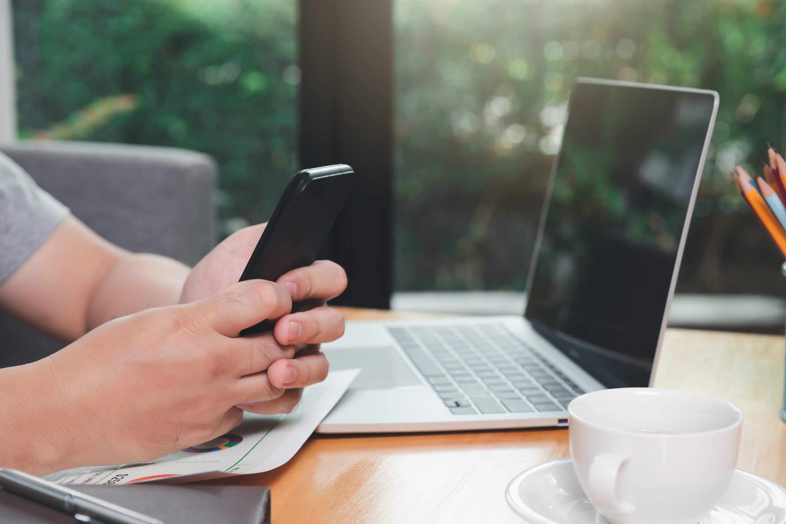 A man holding a smartphone in one corner of the home office; blog: how to combat ad fatigue