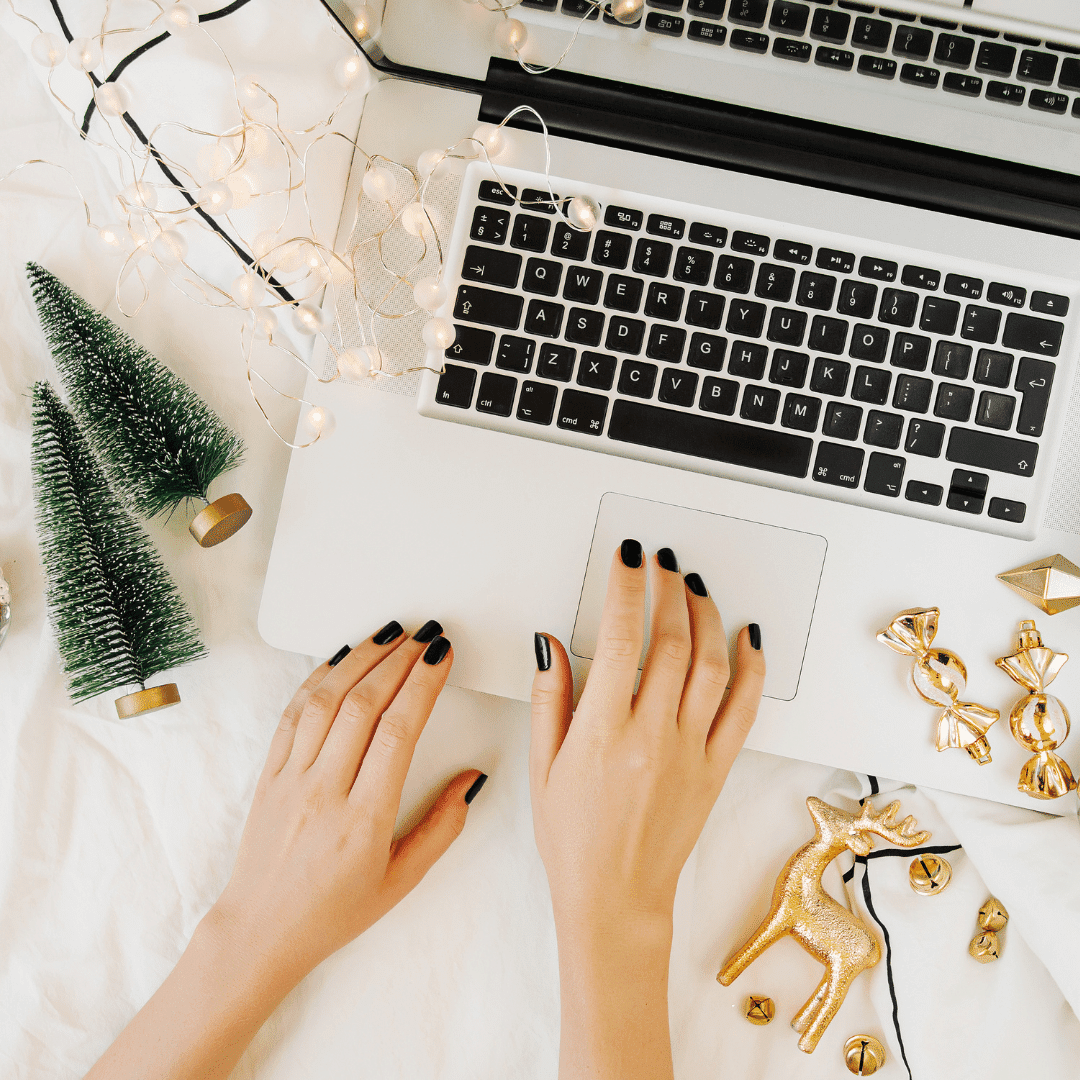 Christmas online shopping. Woman buys presents online. Laptop with Christmas decorations on white bed with a blanket. Holiday concept. Flat lay, top view; blog: helpful holiday marketing tips for small businesses
