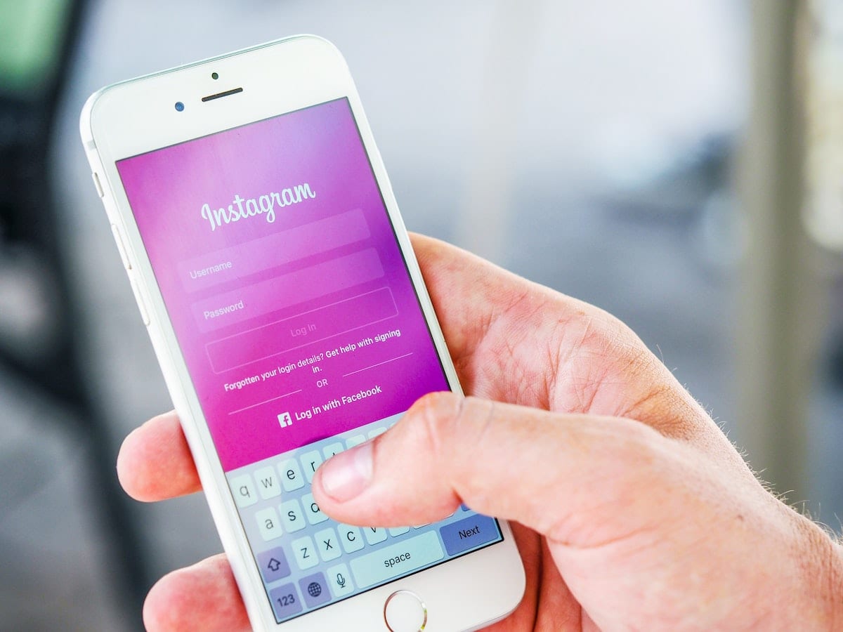 person's hand holding white iphone showing opening screen of instagram app; blog: underutlized instagram features