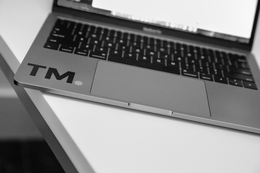 a zoomed in black and white image of a laptop keyboard with a TM sticker to represent a day in the life of an intern at targetmarket